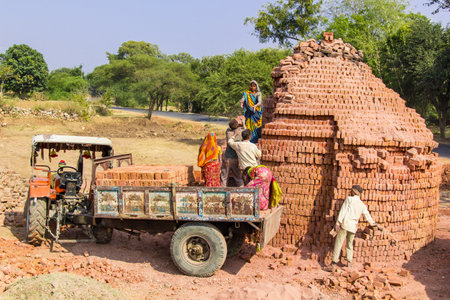 Young Indians load bricks on a tractor  The bricks were fired in a private brickyard のeditorial素材