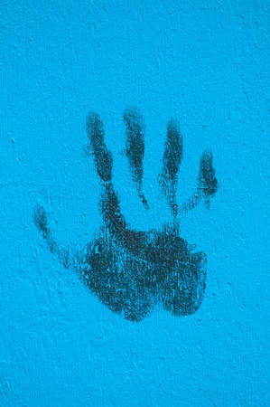 Palm print in black in a blue painted wall の写真素材
