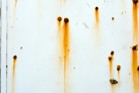 White painted wall with rusting screws showing through.