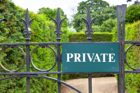 Private sign attached to an ornate wrought iron gate leading into a gardenの写真素材