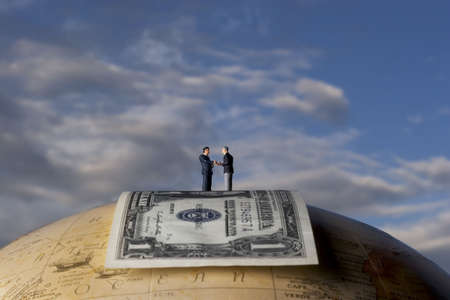 Business figurine placed on globe with moneyの写真素材