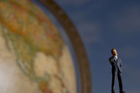 Business figurine placed on or next to an antique earth globe.の写真素材