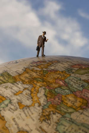 Business figurine placed on or next to an antique earth globe.の写真素材