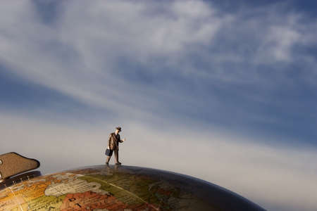 Business figurine placed on or next to an antique earth globe.の写真素材