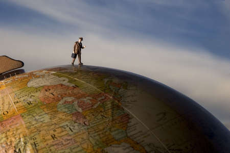 Business figurine placed on or next to an antique earth globe.の写真素材