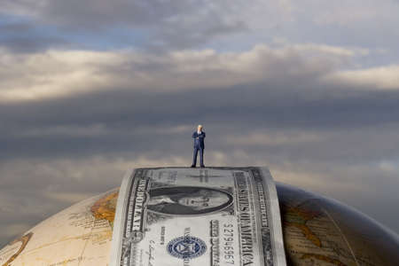 Business figurine placed on earth globe with moneyの写真素材