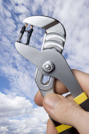 Business figurine held in pliersの写真素材