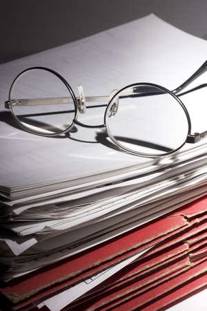 Glasses and stack of papers and foldersの写真素材