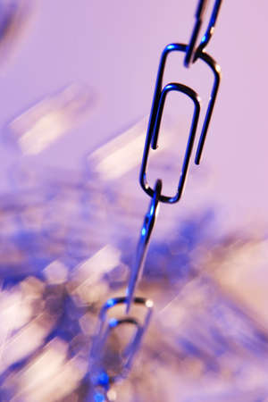 Still life of a chain of paperclips with blue and orange lightingの写真素材