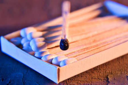 Burnt match and matchbox full of matches laid out on an old piece of woodの写真素材