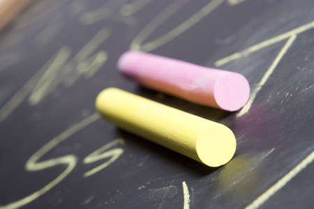 Piece of chalk placed on a chalkboard that has the alphabet written on it.