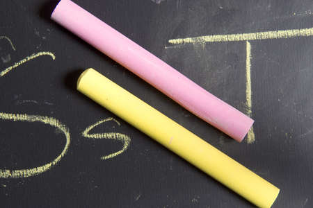 Piece of chalk placed on a chalkboard that has the alphabet written on it.の写真素材