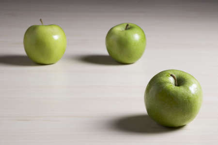 Three green apples on a tabletop  の写真素材