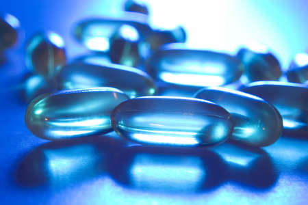 Vitamin E gel tablets illuminated with blue and orange lighting.の写真素材