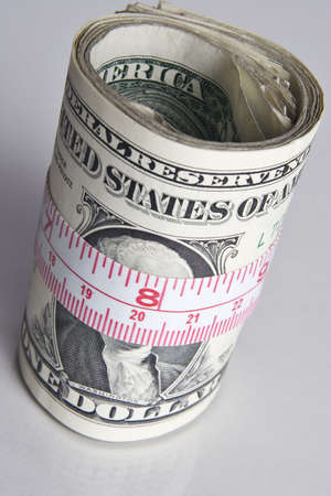 Roll of dollars wrapped with a tape measure の写真素材