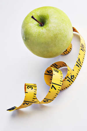 Apple with a tape measure on a reflective tabletop の写真素材
