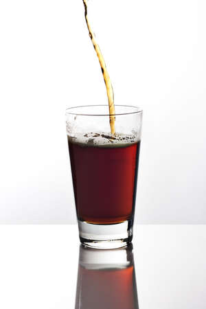 Pouring a glass of dark beer on reflective tabletopの写真素材