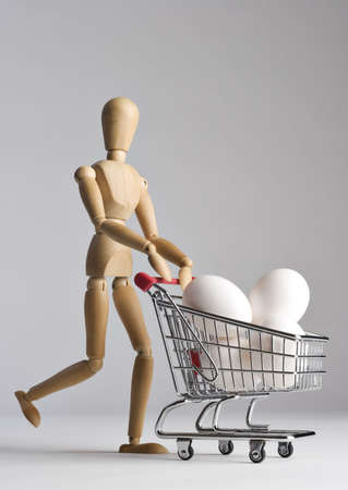Mannequin pushing a shopping cart filled with eggsの写真素材