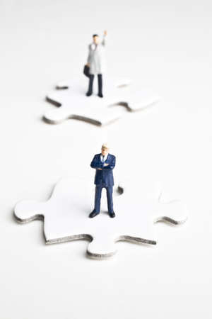 Businessmen figurines standing on puzzle pieces の写真素材
