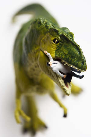 Dinosaur figurine eating a businessman figurine の写真素材