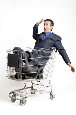 Businessman sitting in a shopping cart looking scaredの写真素材