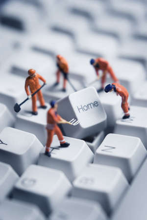 Worker figurines posed to look as though they are working on a computer keyboard.の写真素材