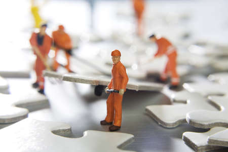 Worker figurines placed with puzzle piecesの写真素材