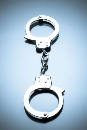 Handcuffs interlocked placed on a reflective tabletopの写真素材