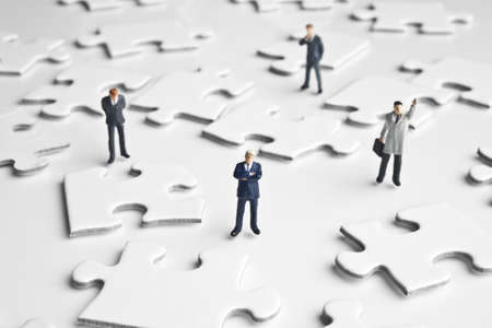 Businessman figurines placed with puzzle piecesの写真素材