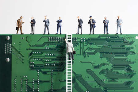 Business figurines and a small ladder placed against a circuit board の写真素材