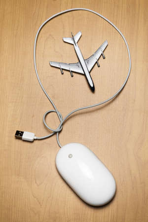 White computer mouse and a toy airplane on a wood tabletopの写真素材