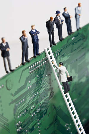 Business figurines and a small ladder placed against a circuit board の写真素材