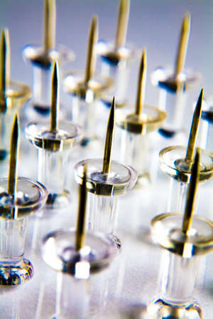 Rows of thumbtacks placed on a white tabletop の写真素材
