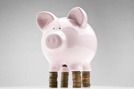 Piggy bank placed on stacks of penniesの写真素材