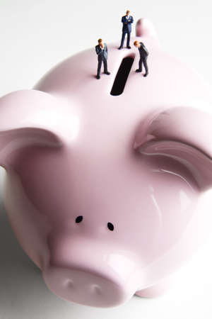 Businessman figurines placed on a piggy bankの写真素材
