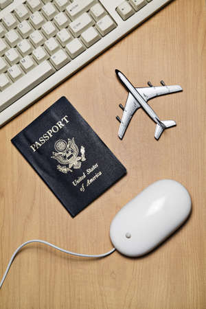 White computer mouse, toy airplane and passport on a wood tabletopの写真素材