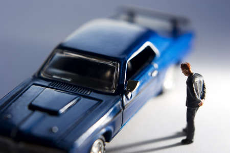 Businessman figurine looking at blue carの写真素材