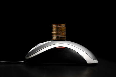 Computer mouse with a stack of coinsの写真素材