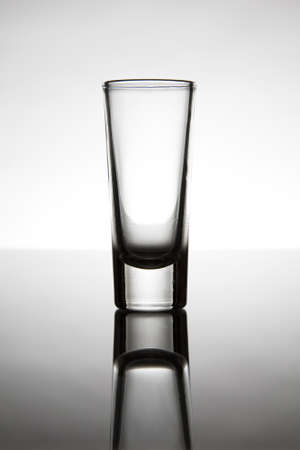 Shot glass on reflective tabletopの写真素材