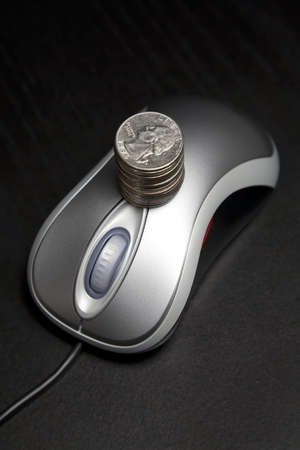 Computer mouse with a stack of coinsの写真素材