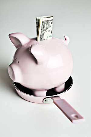 Pink piggy bank and dollar bills in a pink frying panの写真素材