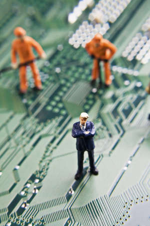 Business and worker figurines placed on a computer circuit boardの写真素材