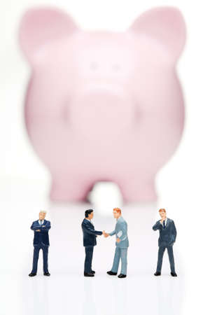 Piggy bank with business figures shaking hands の写真素材
