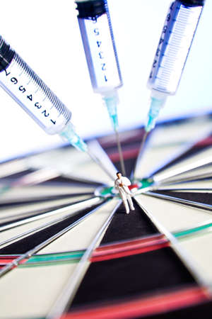 Syringes stuck in a dartboard with medical figures  