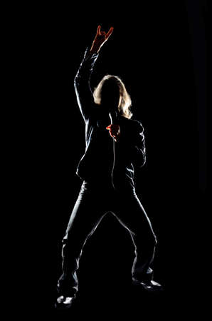 Man with long hair holding a microphone, against a black backgroundの写真素材