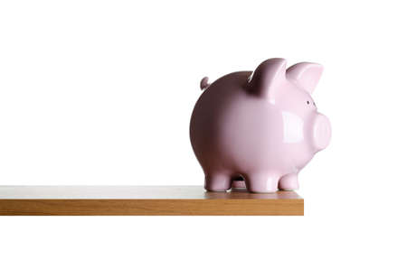 Piggy bank placed close to the edge of a boardの写真素材