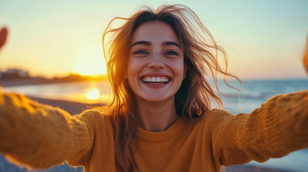 A vibrant person with a beaming smile stands with arms open wide at the beach during sunset, capturing a moment of joy and freedom in nature's beauty.の素材