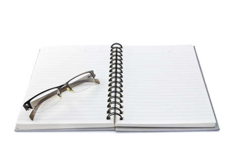 Glasses on spiral notebook isolated on whiteの写真素材