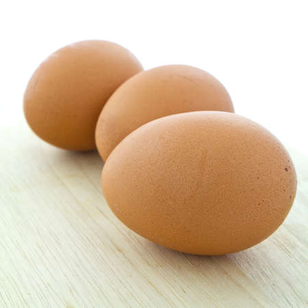 Three eggs on wooden chopping boardの写真素材