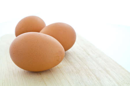 Three eggs on wooden chopping boardの写真素材